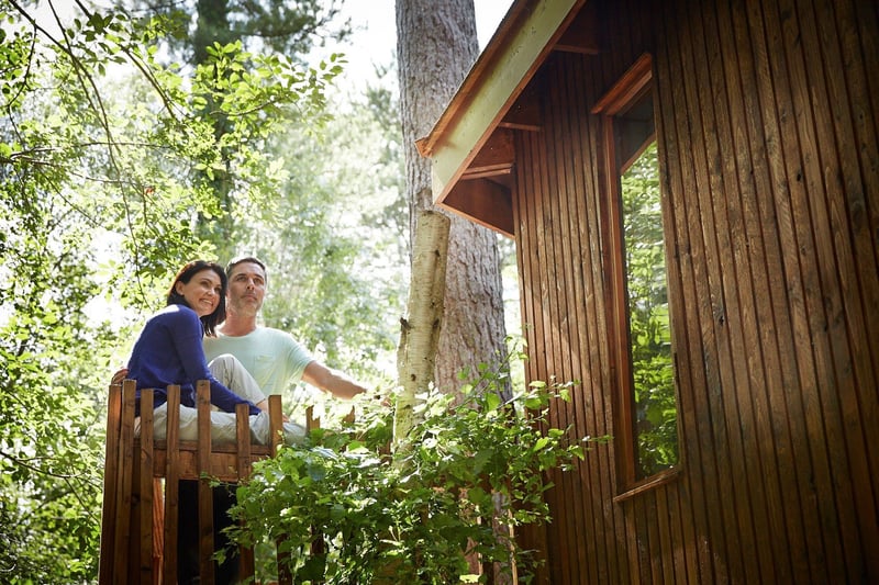 A couple relaxing outside their log cabin at Thorpe Forest, Forest Holidays